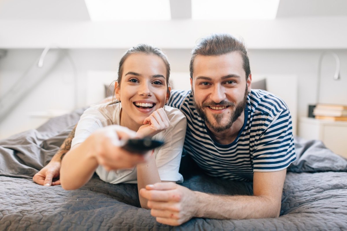 Frau und Mann liegen geimeinsam auf dem Bett und schauen fern.