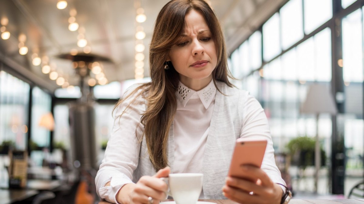 Frau schaut böse auf ihr Handy.