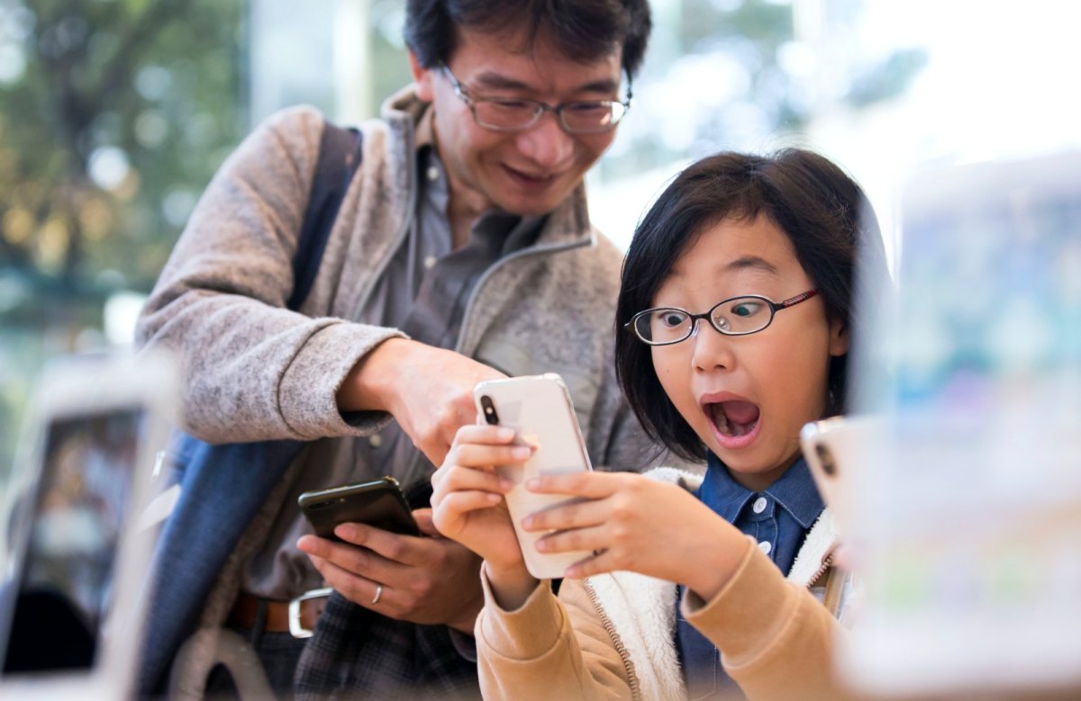 Frau hält iPhone X in der Hand und macht begeistertes Gesicht.