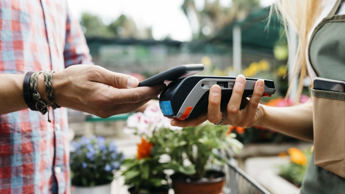 Ein Kunde zahlt auf dem Wochenmarkt mit seinem Smartphone