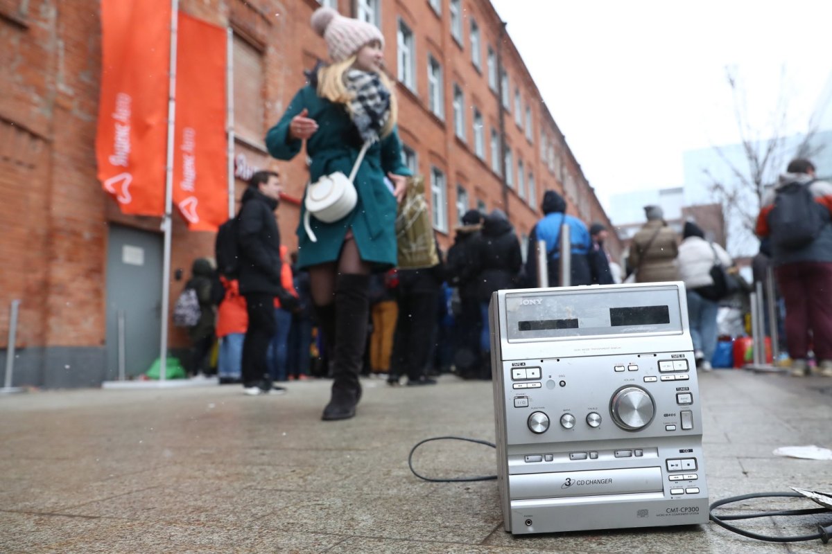 CD-Player steht auf Straßenboden vor Menschen.