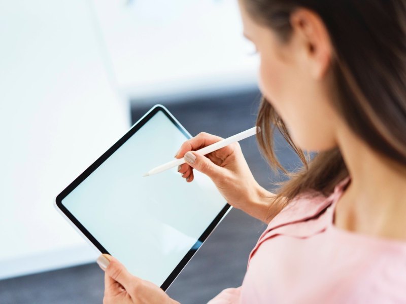 Frau schreibt auf einem Tablet.