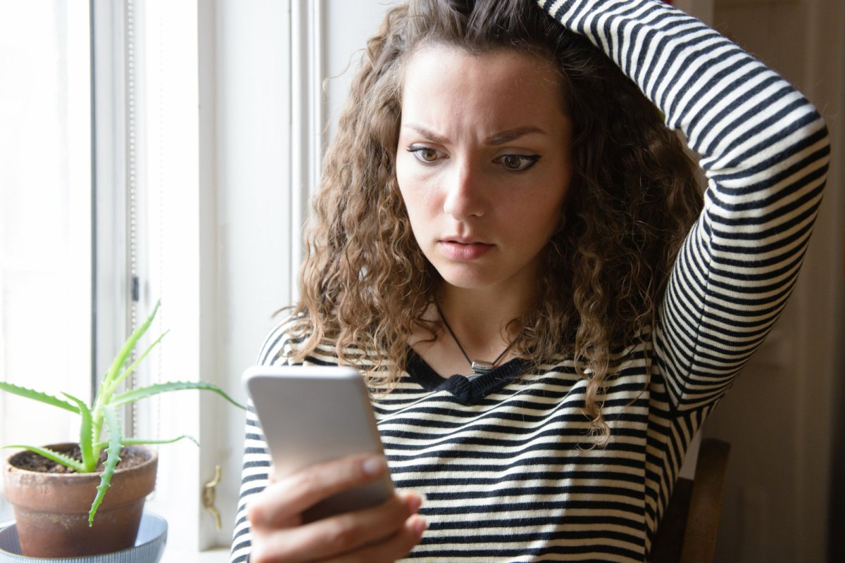 Frau schaut geschockt auf ihr Handy.