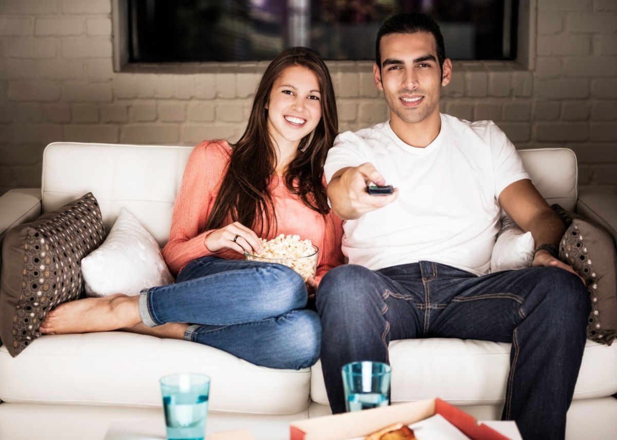 Mann und Frau mit Popcorn auf der Couch.