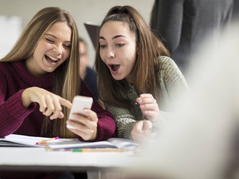 Junge Mädchen schauen erstaunt auf ein Smartphone