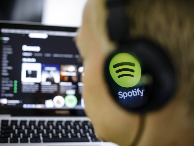 Person vor dem PC mit Spotify-Kopfhörern.