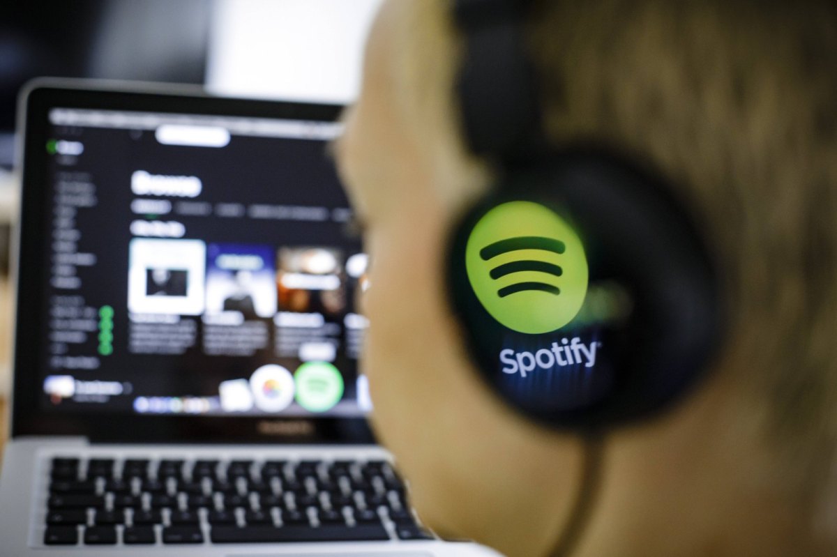 Person vor dem PC mit Spotify-Kopfhörern.