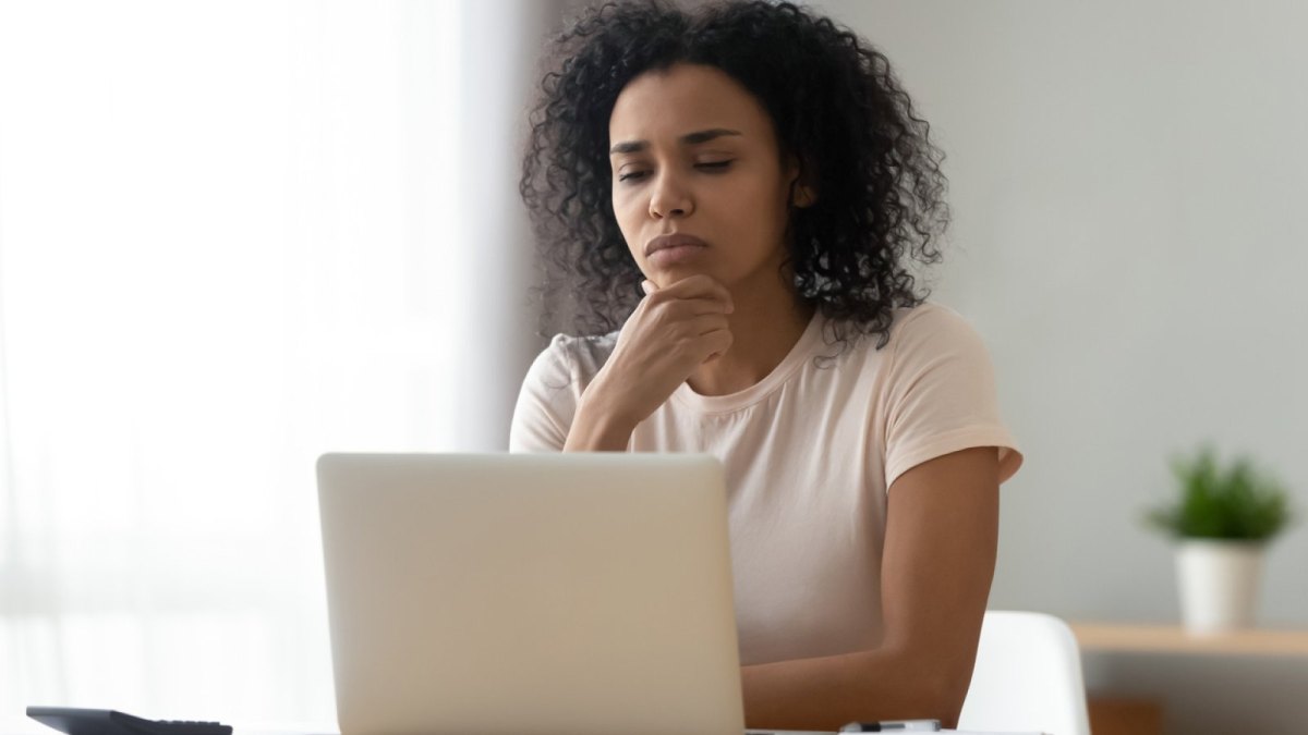 Frau sieht nachdenklich auf ihren Laptop.