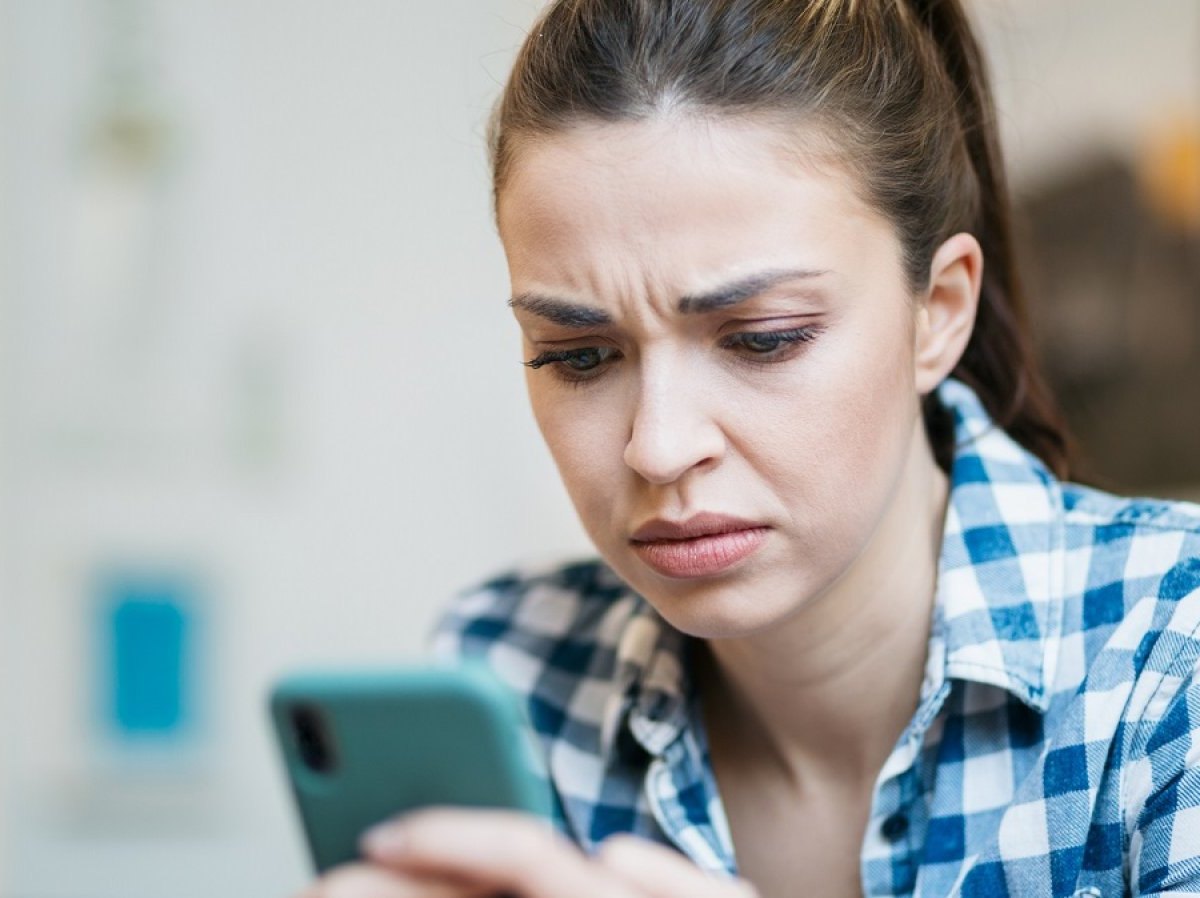 Frau schaut fragend auf ihr Handy.