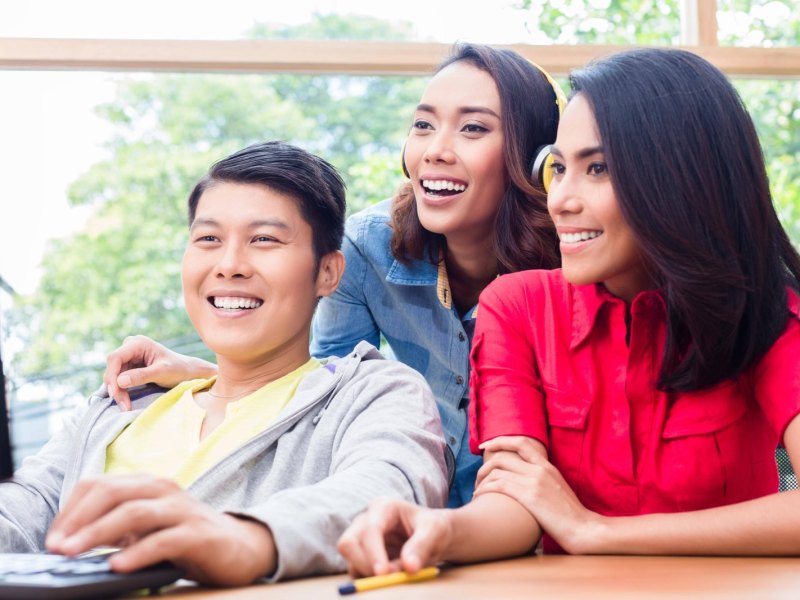 drei freunde lachen über inhalte auf dem pc