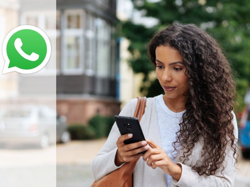 Frau schaut auf Handy Whatsapp Logo