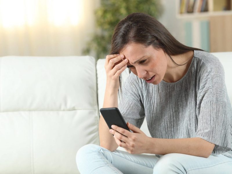 Frau schaut besorgt auf Smartphone