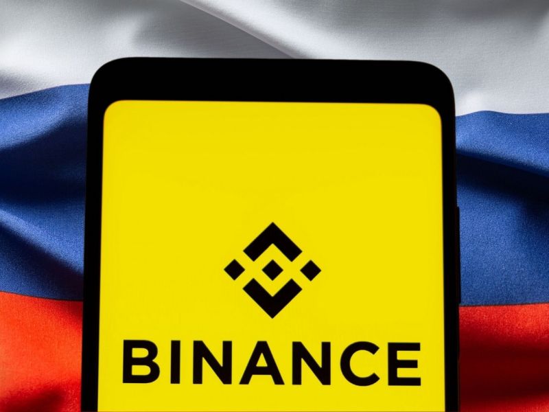 Binance-Logo vor einer Russland-Flagge