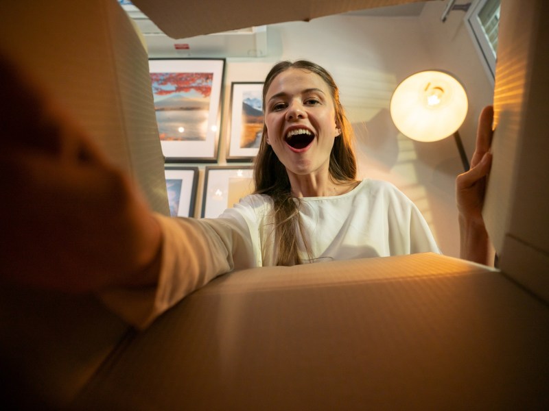 Frau schaut freudig in ein Paket