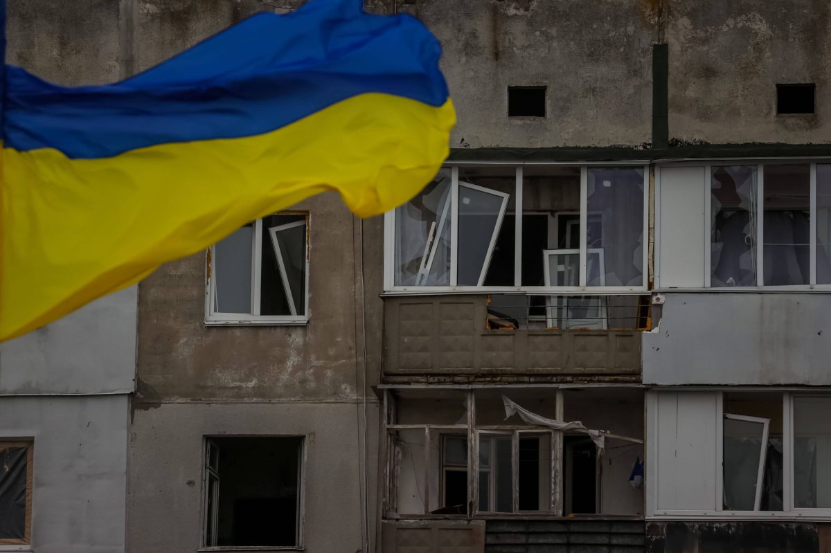 Ukrainische Flagge weht vor verwüstetem Gebäude