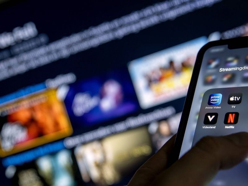 Smartphone mit Streaming-Apps, im HIntergrund ein TV.