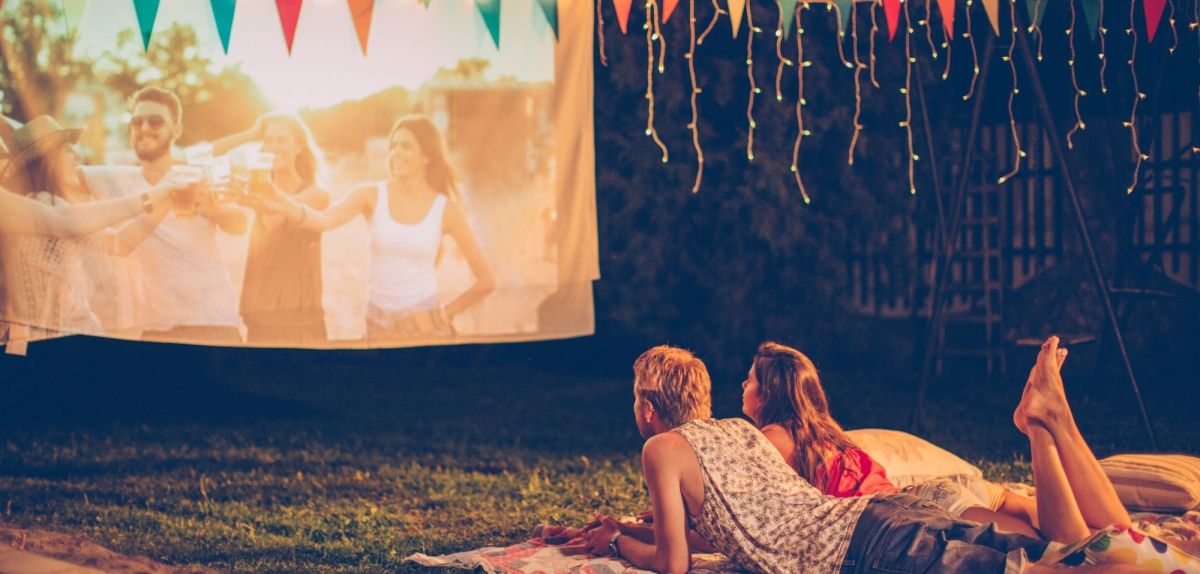 Paar liegt auf der Wiese vor einer Filmleinwand.