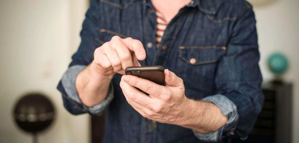 Mann tippt mit Finger auf sein Smartphone.