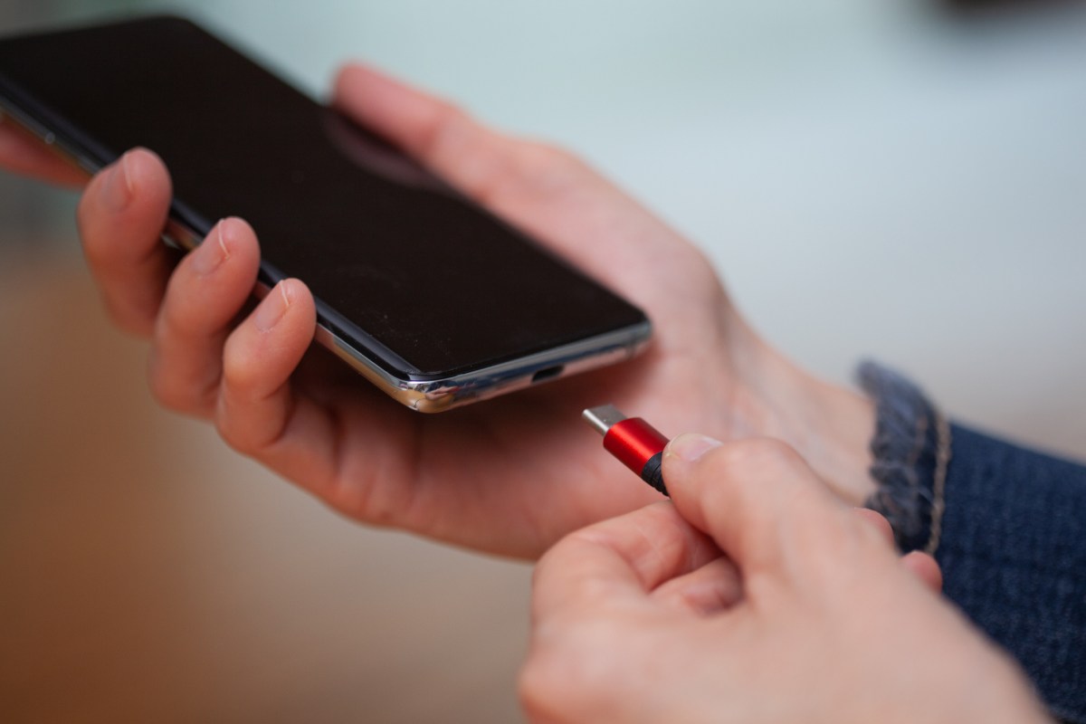 Ein Ladekabel wird an ein Handy und dessen Akku angeschlossen