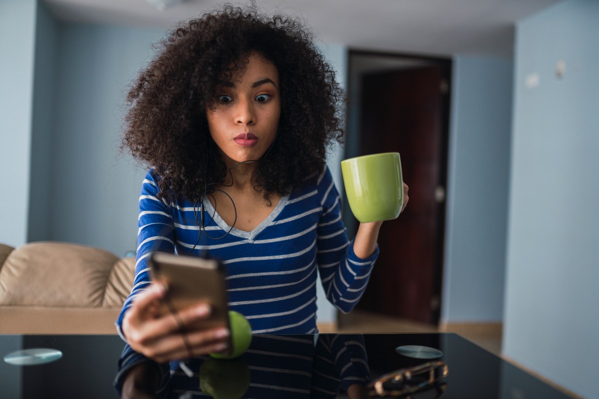 Frau mit Handy und Tasse in der Hand