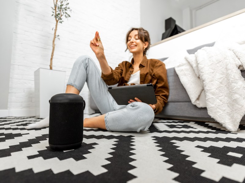 Frau mit Smart Speaker auf dem Boden