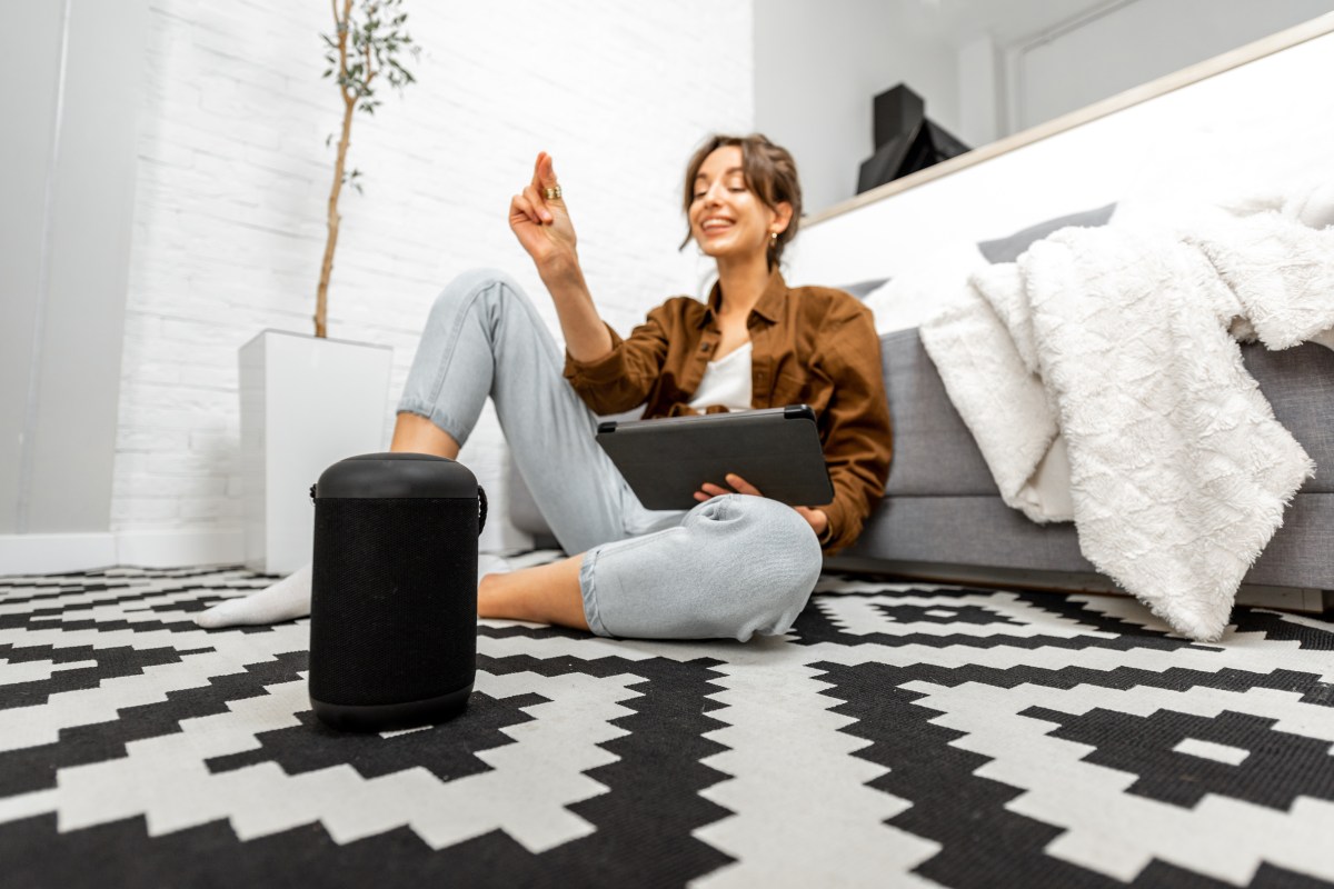 Frau mit Smart Speaker auf dem Boden