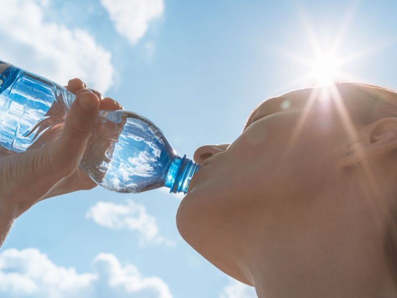 Frau trinkt Wasser aus einer Flasche.