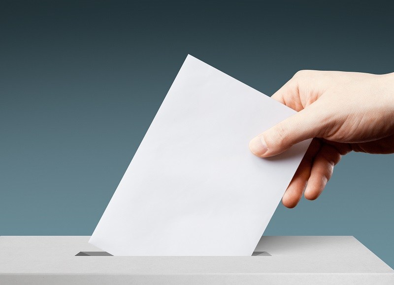 Mann steckt Wahlzettel in Urne