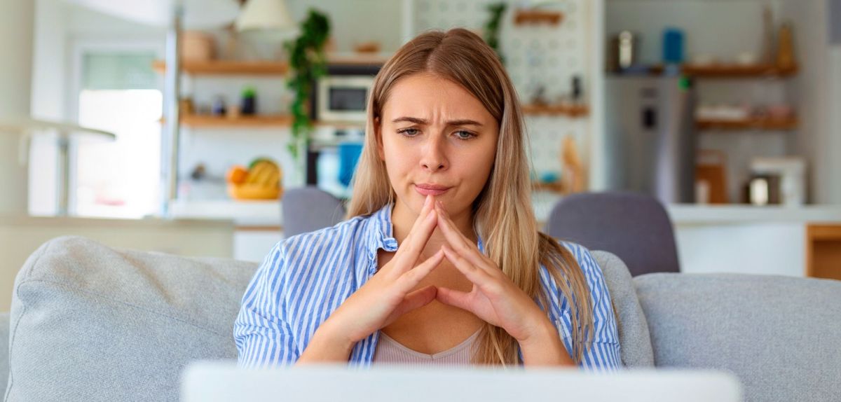 Frau blickt nachdenklich auf ihren Laptop