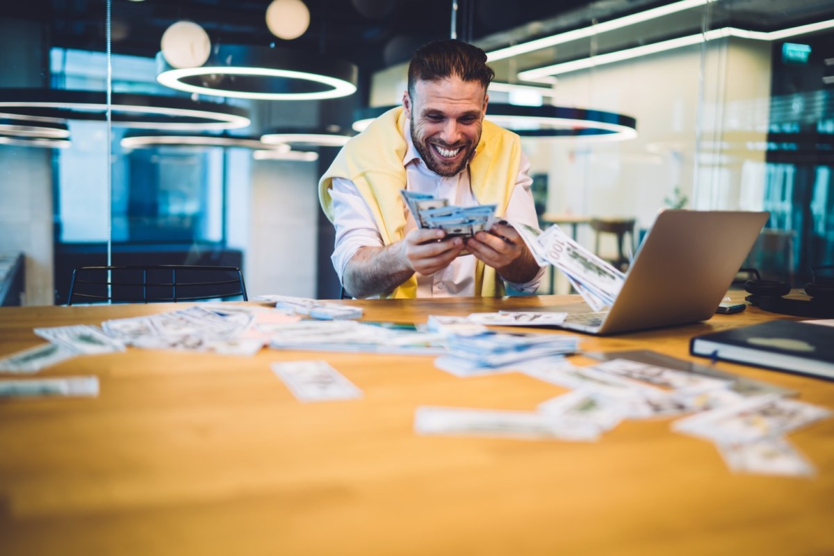 Mann mit Geld in der Hand am Laptop