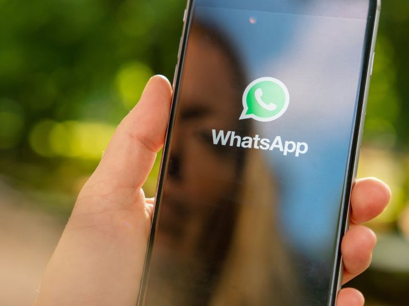 WhatsApp auf dem Handy, im Hintergrund ein Park