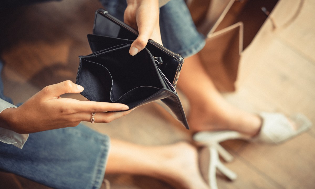 Frau hÃ¤lt ein leeres Portemonnaie in der Hand.