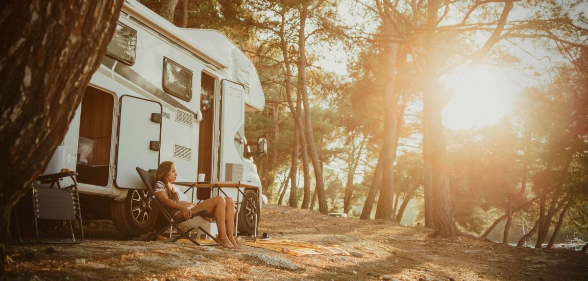 Frau campt nachhaltig im Wald mit Wohnmobil