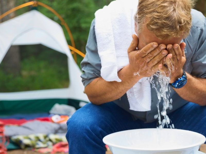 Mann wäscht sich das Gesicht beim Camping