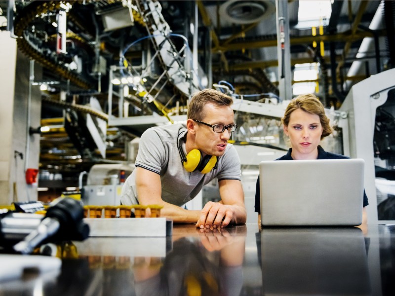 Mann und Frau in einem technischen Beruf. Sie schauen auf einen Laptop.