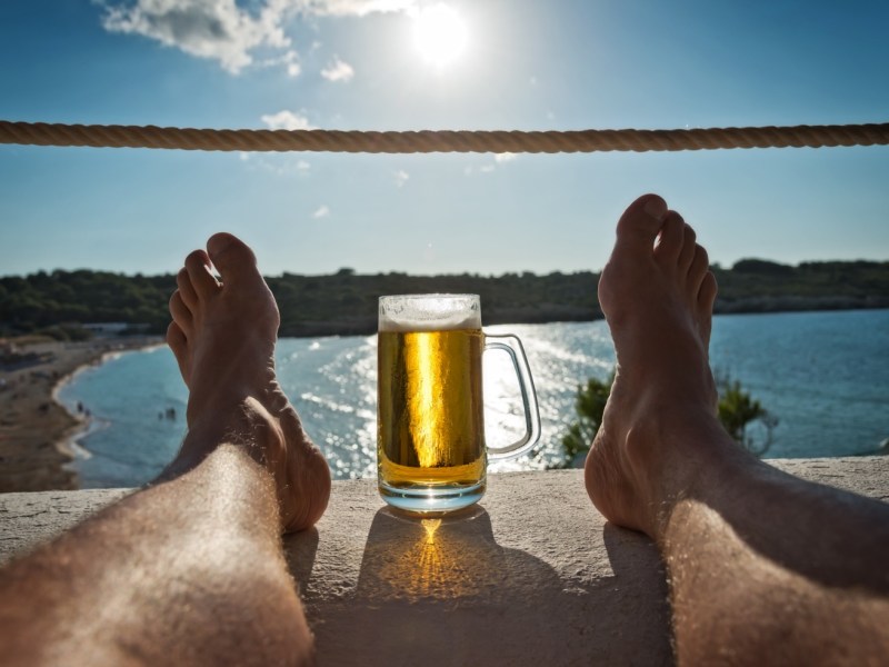 Bier am Meer zwischen zwei Füßen