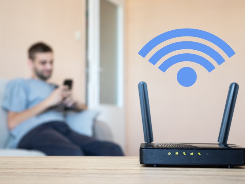 Mann sitzt auf dem Sofa nahe einem Router