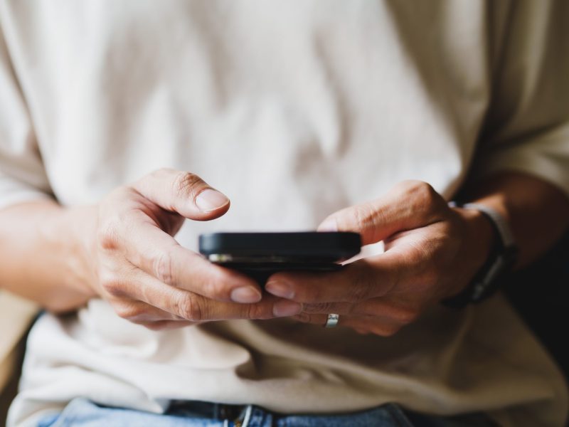 Eine Person tippt mit beiden HÃ¤nden am Smartphone.