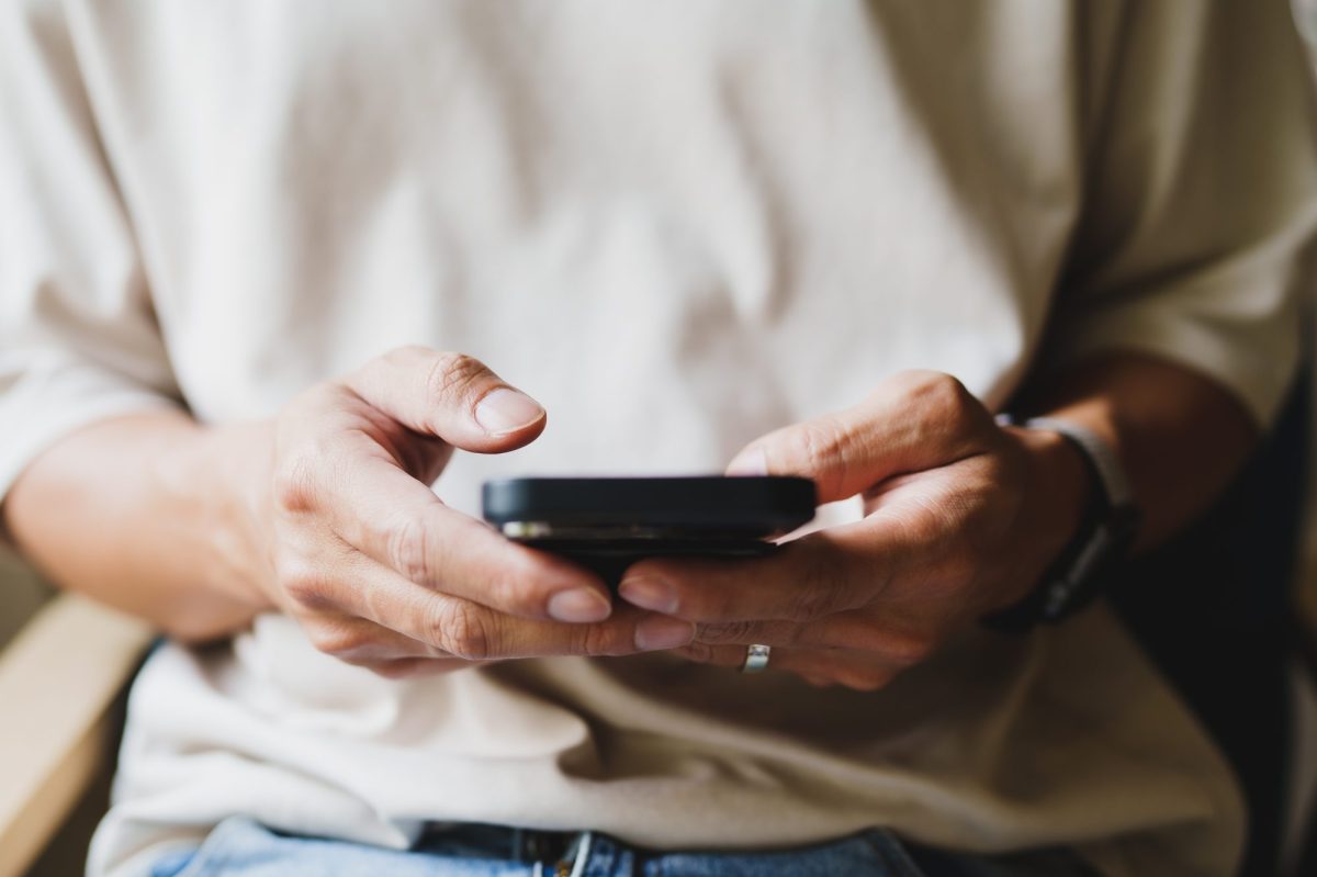 Eine Person tippt mit beiden HÃ¤nden am Smartphone.