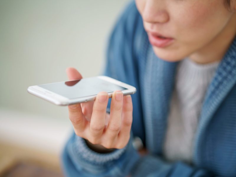 Eine Frau spricht auf ihrem Smartphone mit Siri.