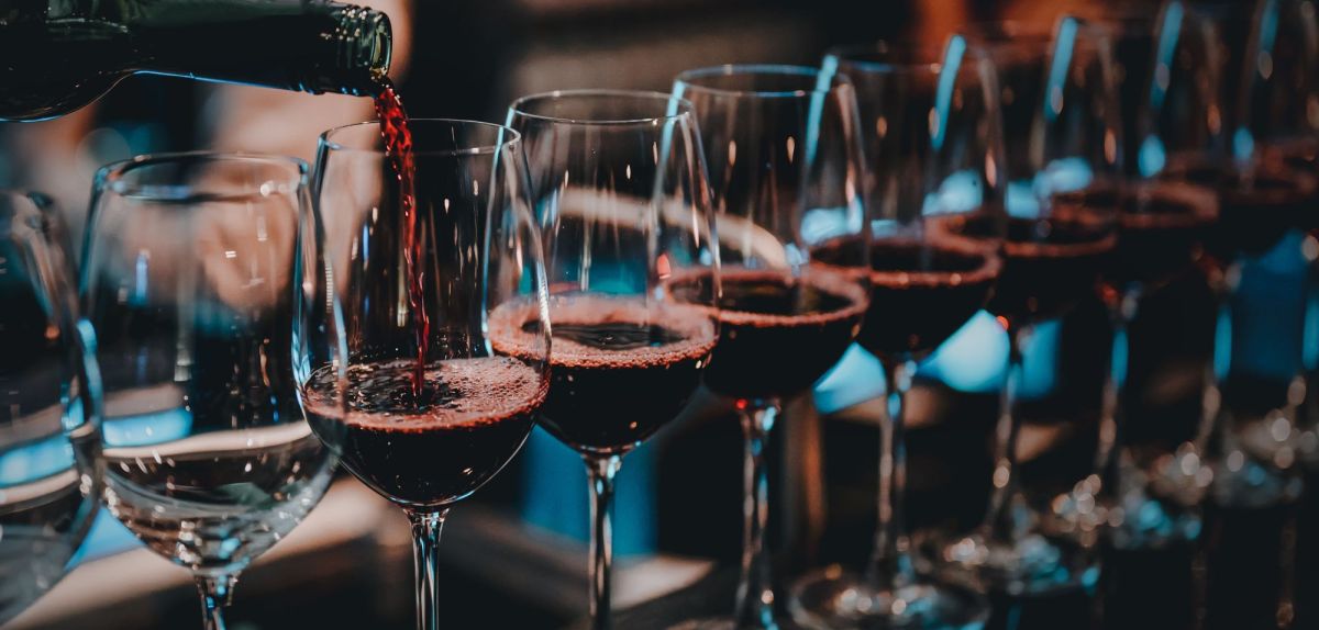 Mehrere Gläser Rotwein nebeneinander aufgereiht.