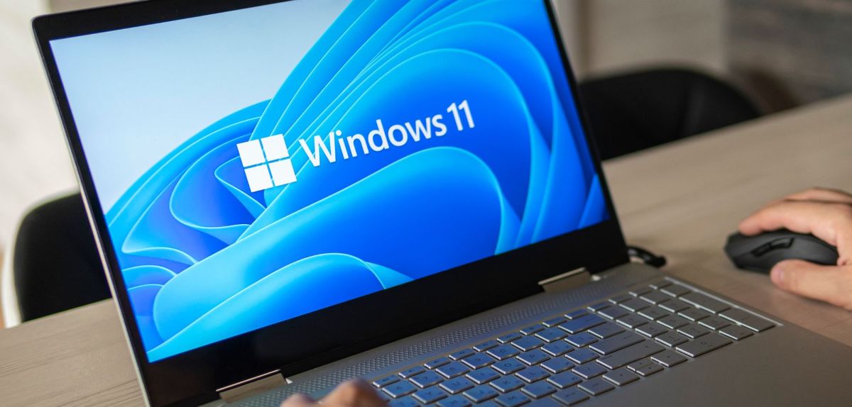 Person sitzt an einem Laptop mit Windows 11.