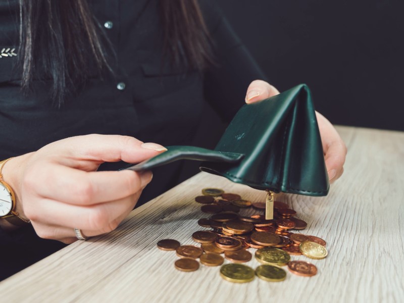 Person schÃ¼ttet MÃ¼nzen aus einem Portemonnaie.