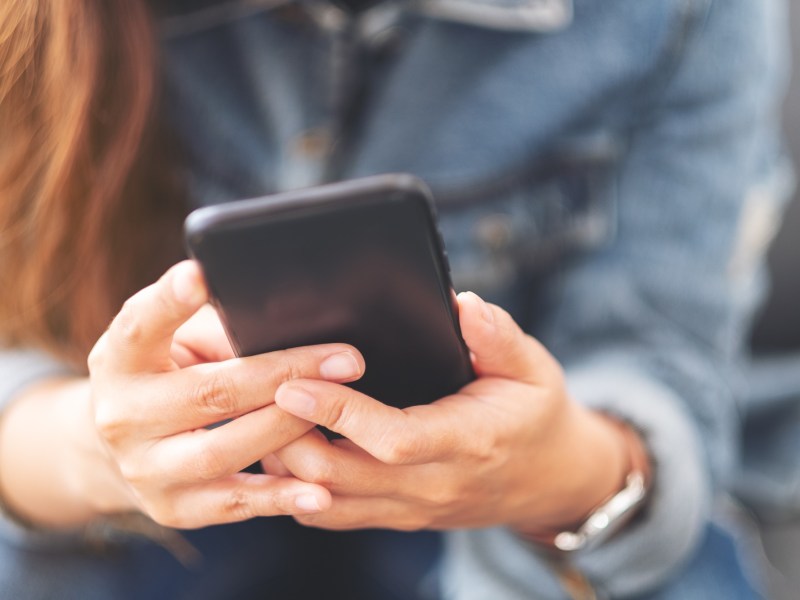 Eine Frau hÃ¤lt ein Handy in beiden HÃ¤nden