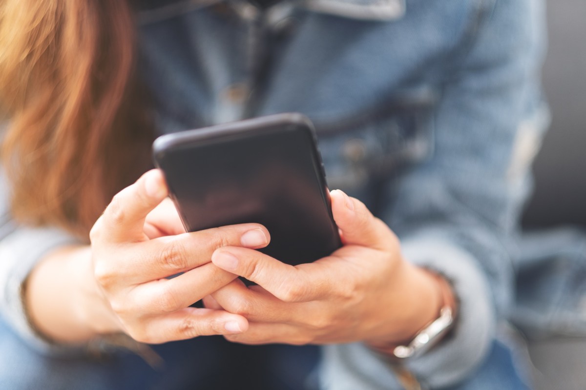 Eine Frau hält ein Handy in beiden Händen