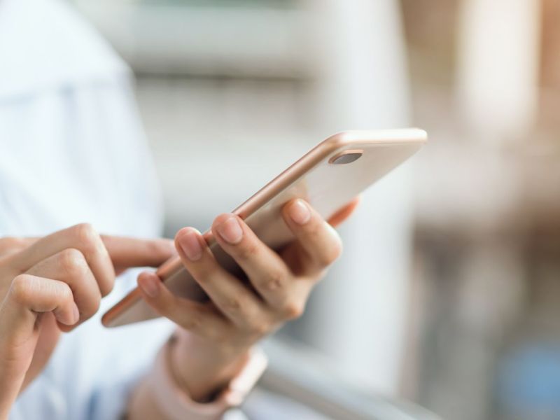 Frau hÃ¤lt ein Smartphone in der Hand.