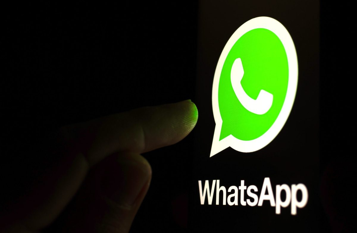 Ein Finger berÃ¼hrt ein riesiges WhatsApp-Logo im Dunklen.