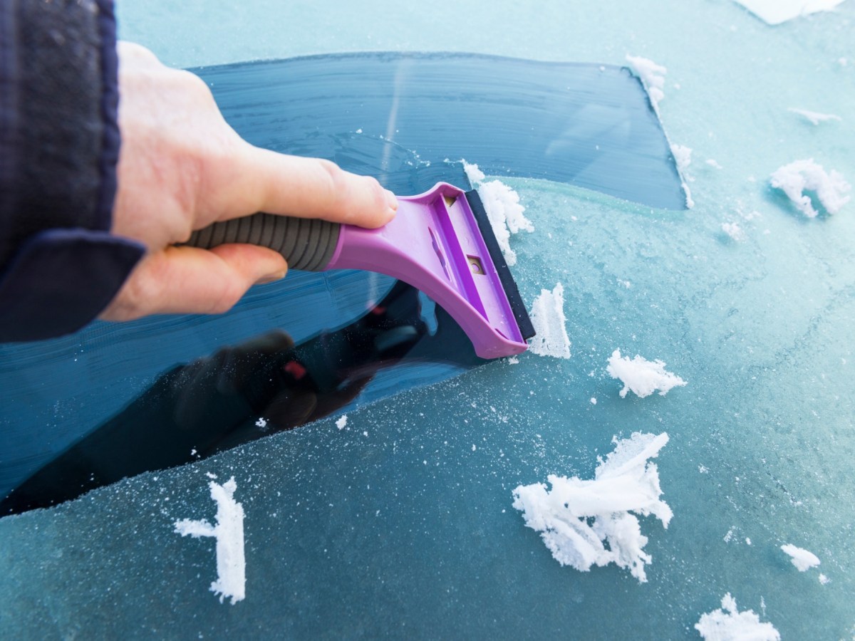 Person kratzt eine Autoscheibe frei