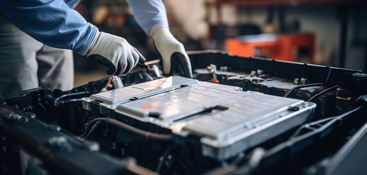 Mechaniker arbeitet an einer Batterie in einem Elektroauto.