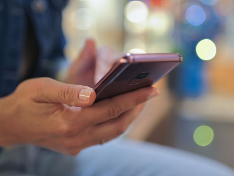 Person hÃ¤lt ein Smartphone in der Hand.